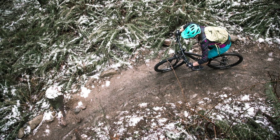 Aerial shot of a woman riding a mountain bike on a singletrack trail