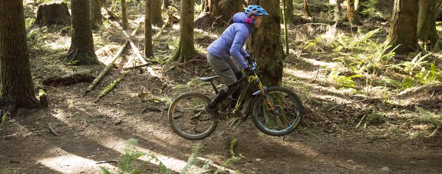 A rider practices a bunny hop on her mountain bike