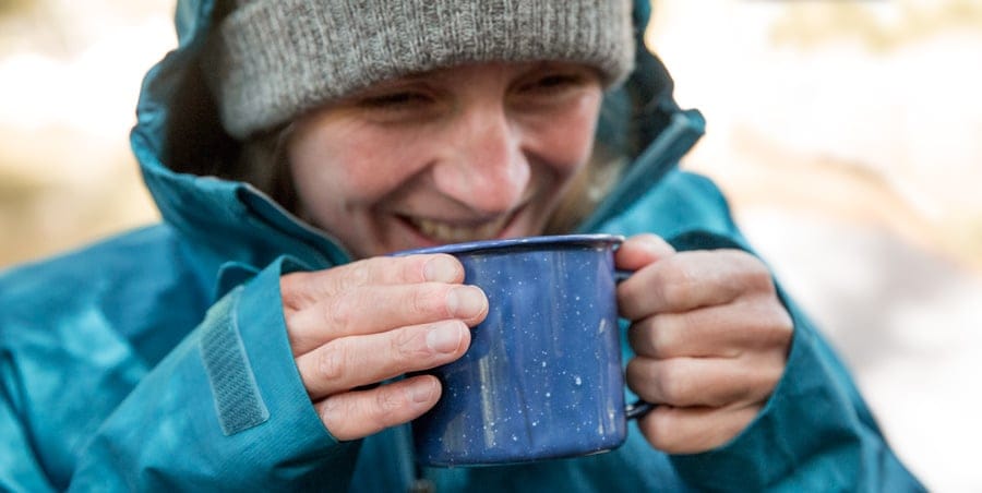 a camper enjoying a warm beverage before going to sleep in their tent