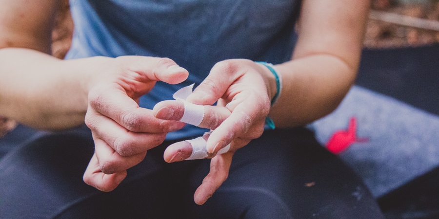 A climber tapes her fingers before bouldering.