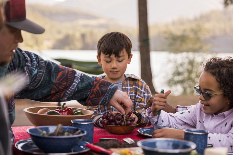 Two children eat at a picnic table.