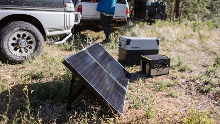 A solar panel absorbs energy from sunlight and provides electricity to a portable power station and an electric cooler