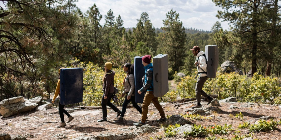 A group of climbers walks on a path to get to a bouldering location.