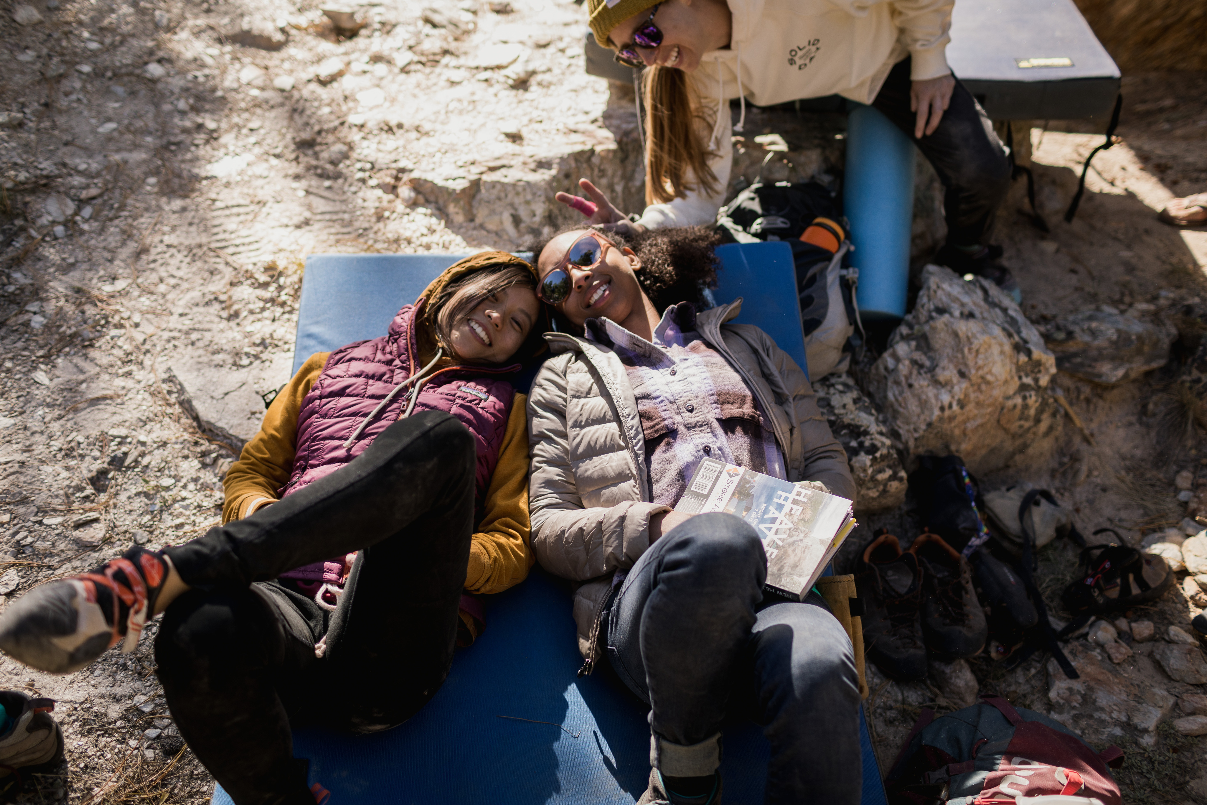 Female climbers lounge at the bottom of the route on their crash pad