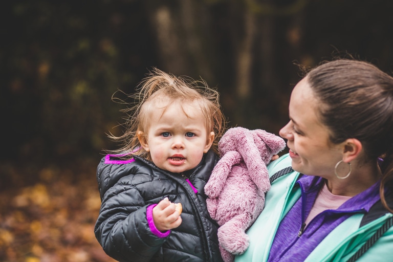 Woman holds a young girl in her arms. They are dressed for the outdoors.