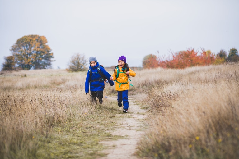 Young boy and girl run along a trail.