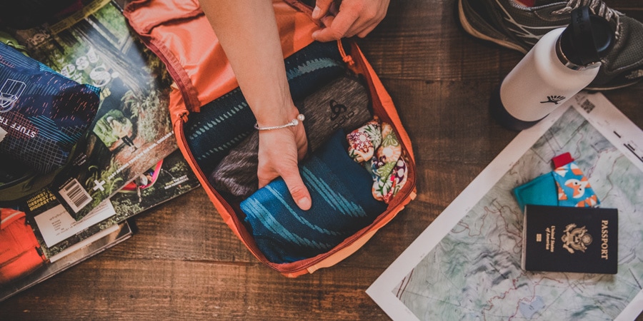 a traveler packing their bag using packing cubes