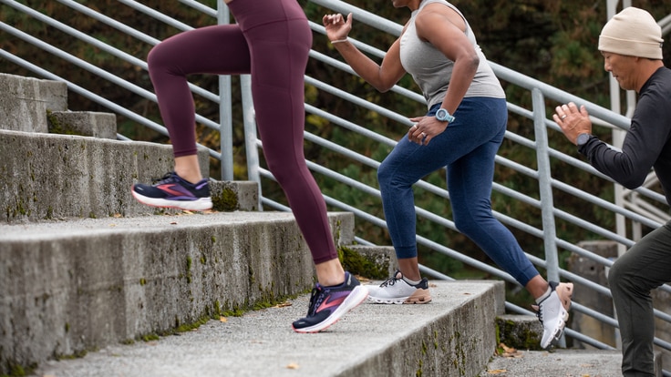 Three people wearing fitness clothing run upstairs