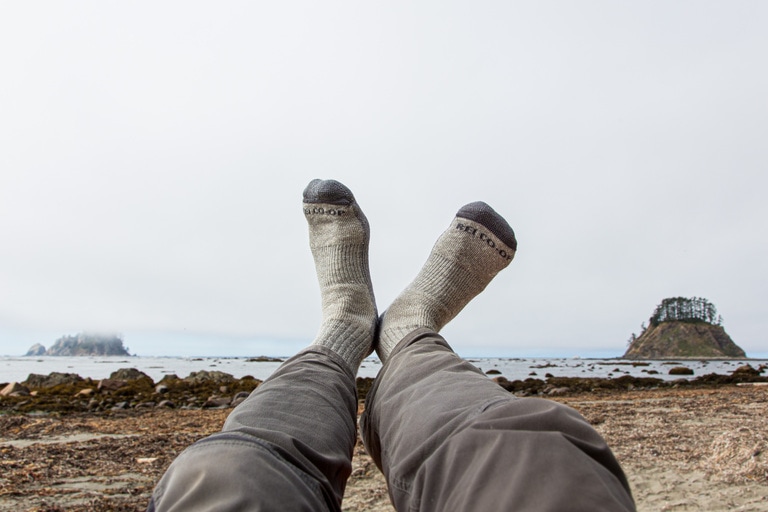 A person with socked feet in the air with coastal background