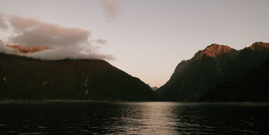 A scene of a body of water with mountains in the background