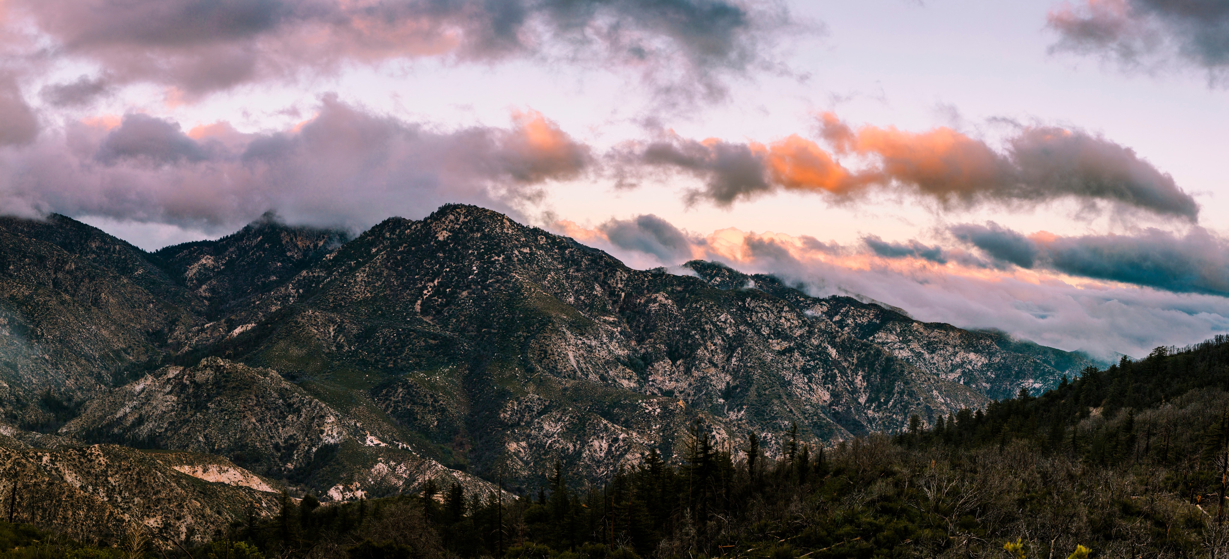 A mountain with clouds above at sunset