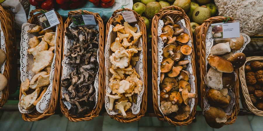 a spread of mushrooms and vegetables at an outdoor food market