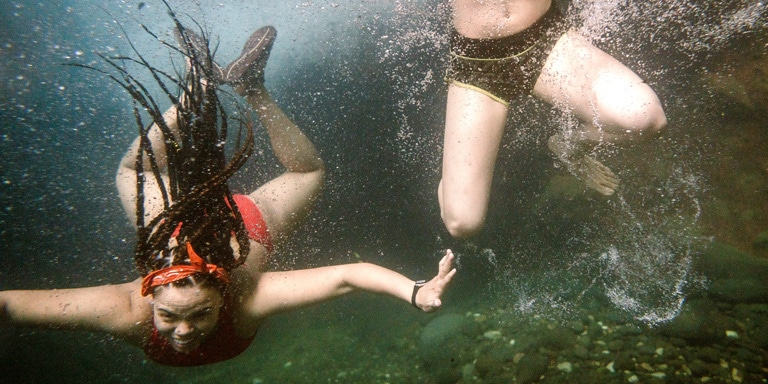 Underwater shot of 2 women as they jump into a lake