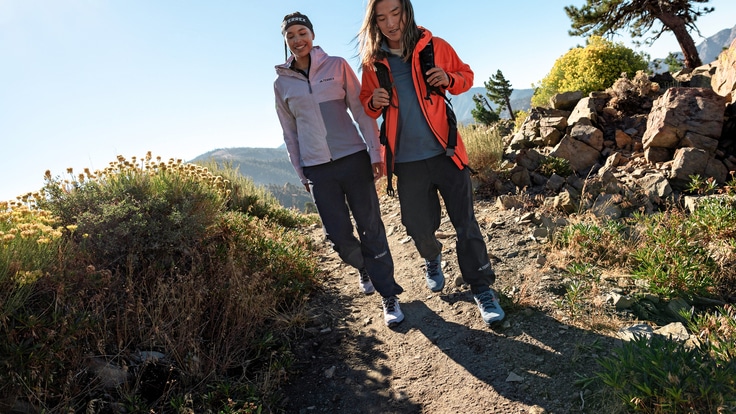 Two smiling people hike through a rocky pass.