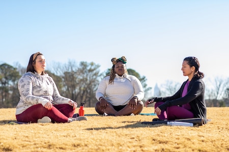 Three women sit on grass relaxing