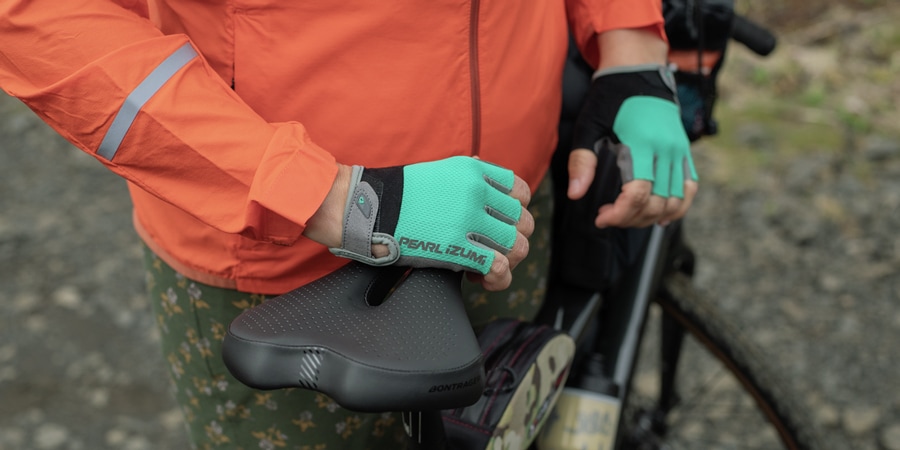 Cyclist with bike gloves, hands resting on bike saddle