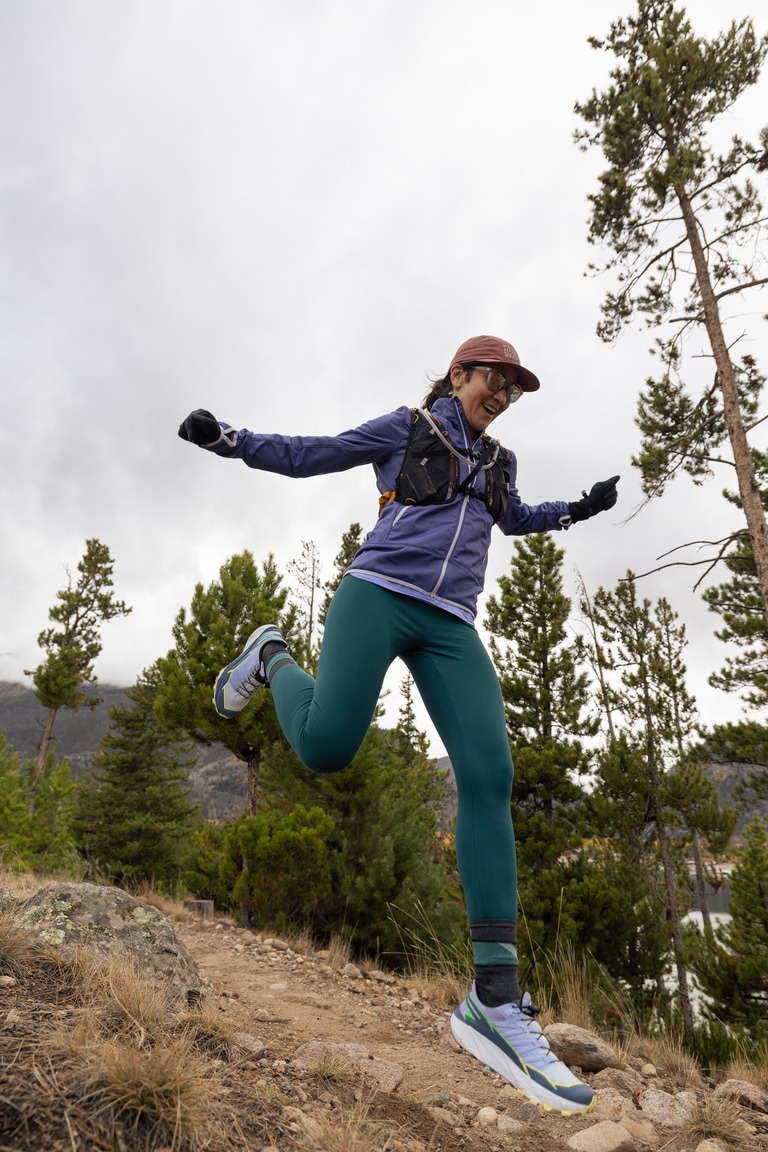 A woman leaping down a trail in the Salomon Thundercross trail-running shoes