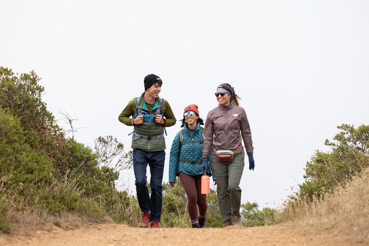 three hikers walking up a dirt trail