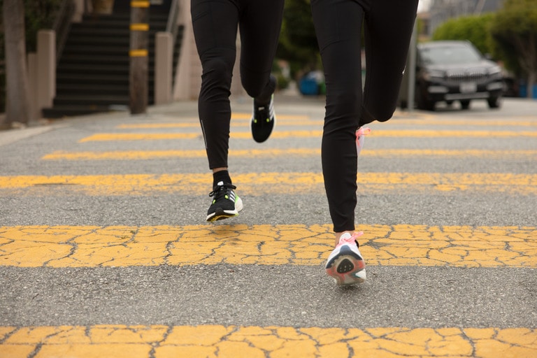 Two runners bounding down the road in the Ultraboost 22 road running shoes.