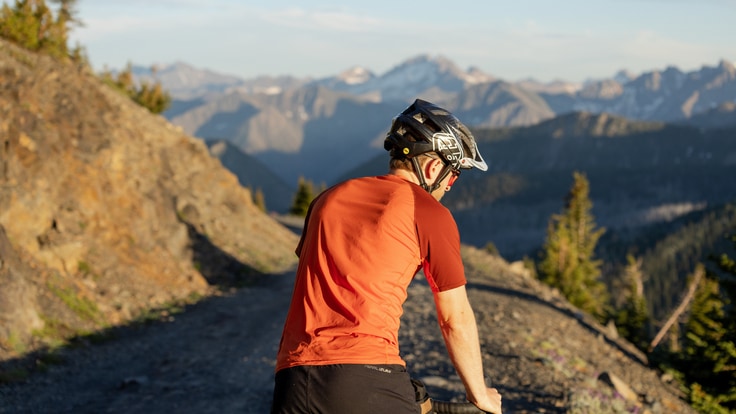 A cyclist with bike helmet stops at side of gravel round