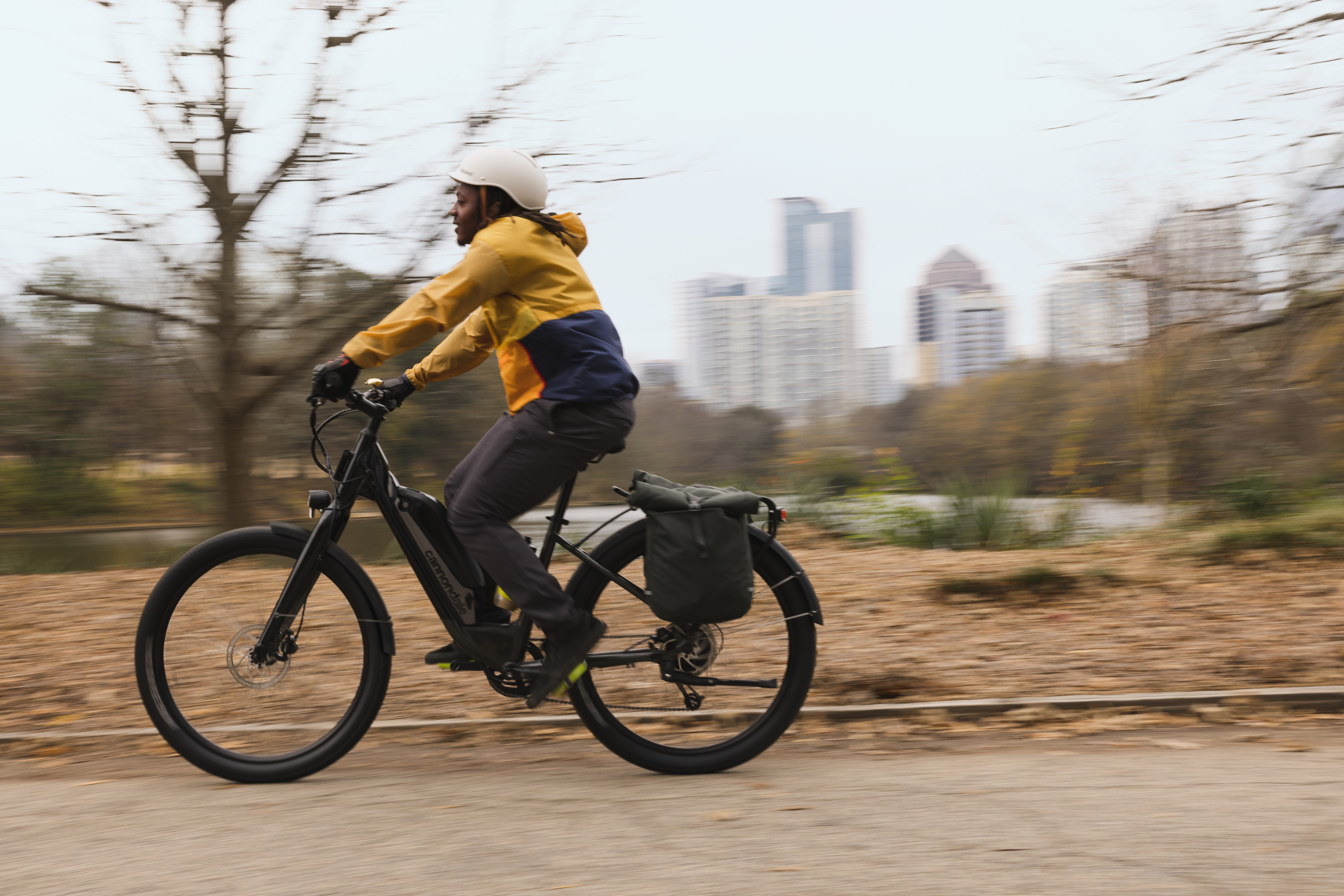 A person riding an electric bike past an urban skyline.