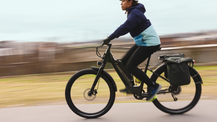 Two people wearing casual clothes biking on a path near water.