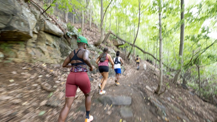 A group of runners running uphill on a trail