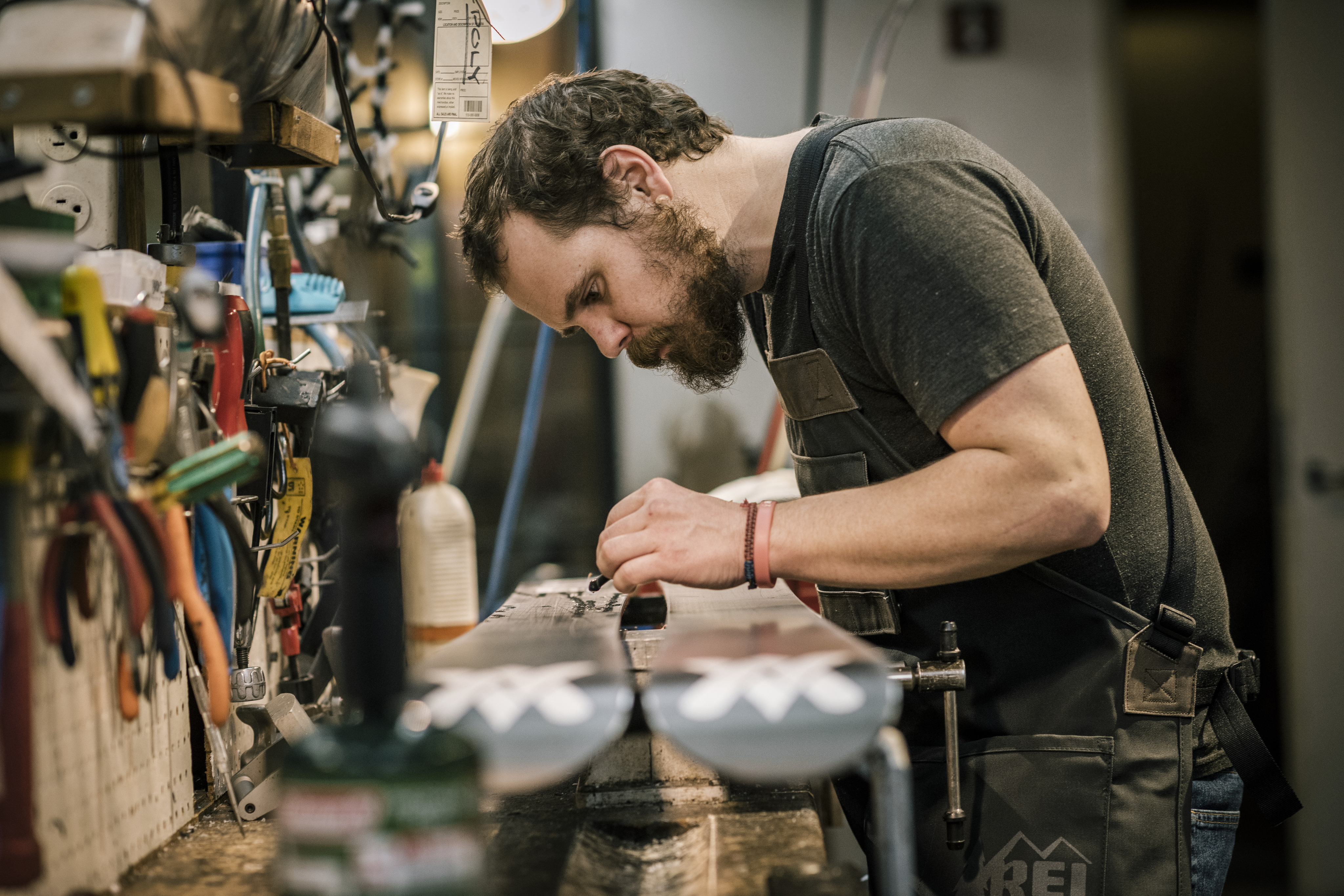 A shop technician carefully inspects a pair of skis.