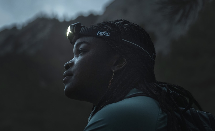 A person wears the Petzl Actik Core Headlamp.