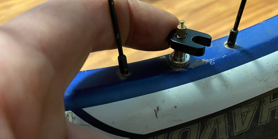 person removing a valve core from a bike rim