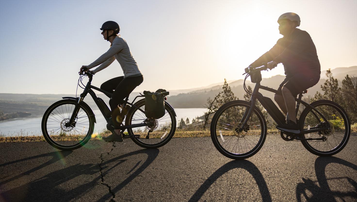 Two people riding e-bikes along a path