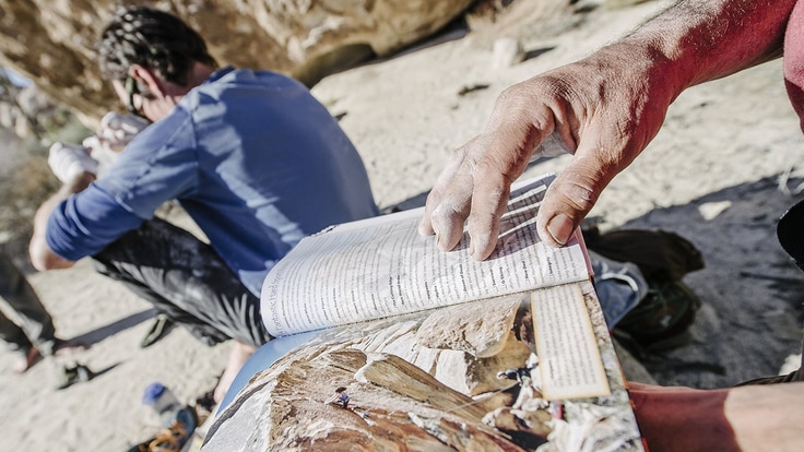 a climber reading a rock climbing fieldguide book