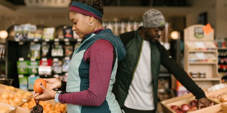 A woman and man choose select groceries from a market.