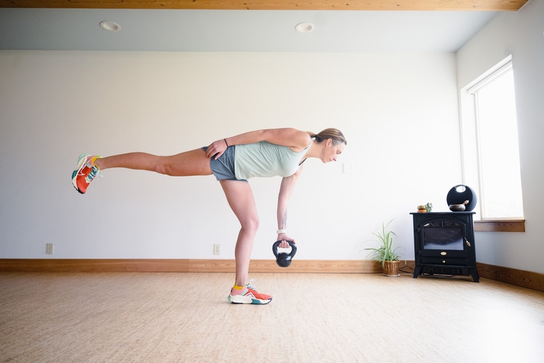 A woman performs a single leg deadlift with a kettlebell