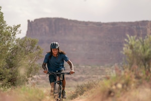 A cyclist biking on a trail wearing a helmet