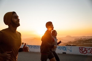 Two men running with friends on a road wearing short sleeves and shorts