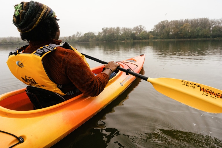 An image from behind of a person paddling in their PFD.