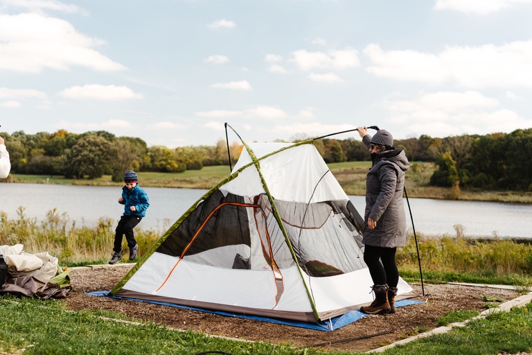 Young boy and woman set up a tent.