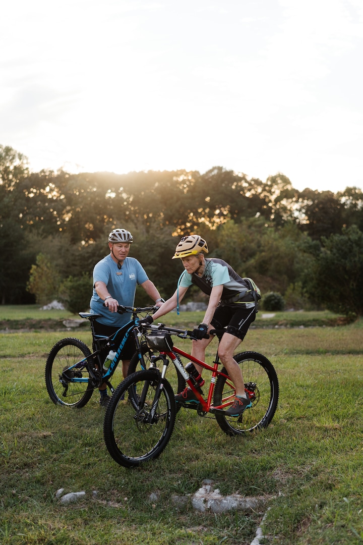 A person riding a mountain bike while a coach provides tips