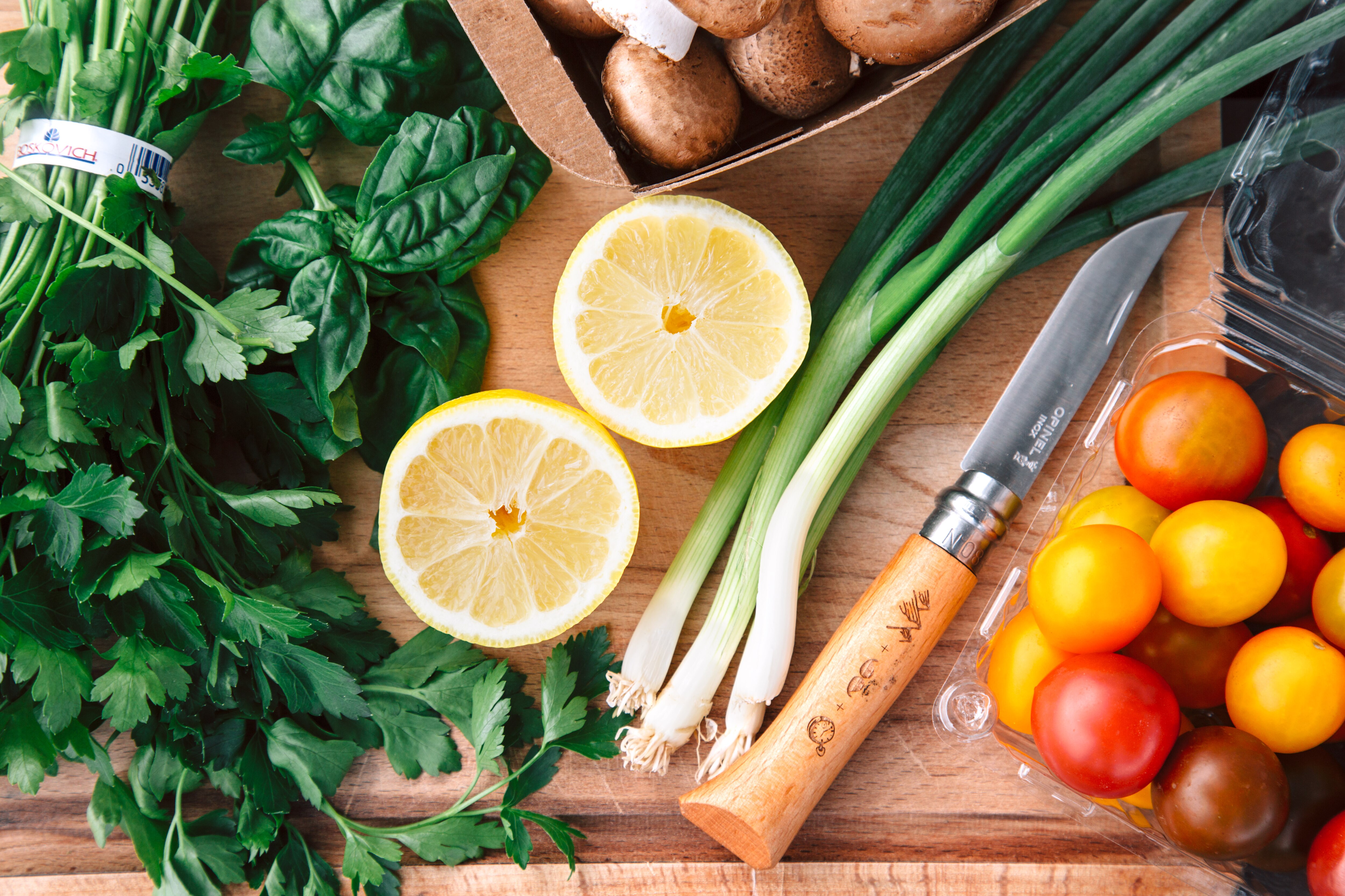 Photo of produce, including a halved lemon, cherry tomatoes and basil.