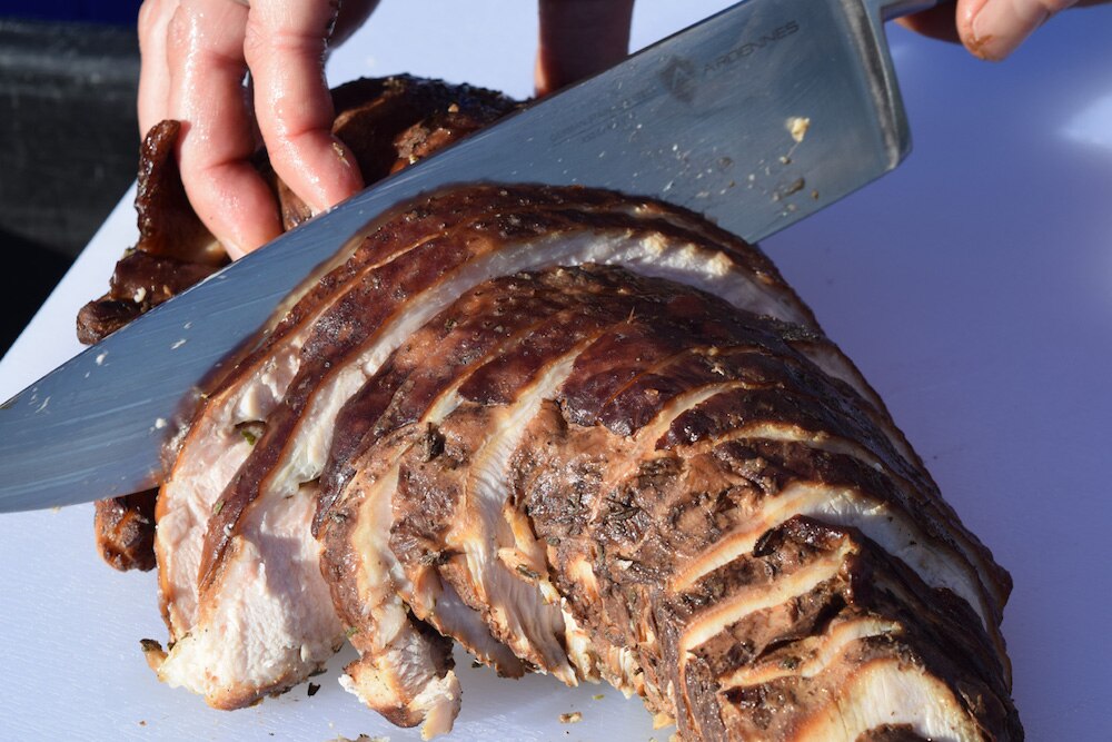 A person cutting into Applewood Smoked Turkey Breast