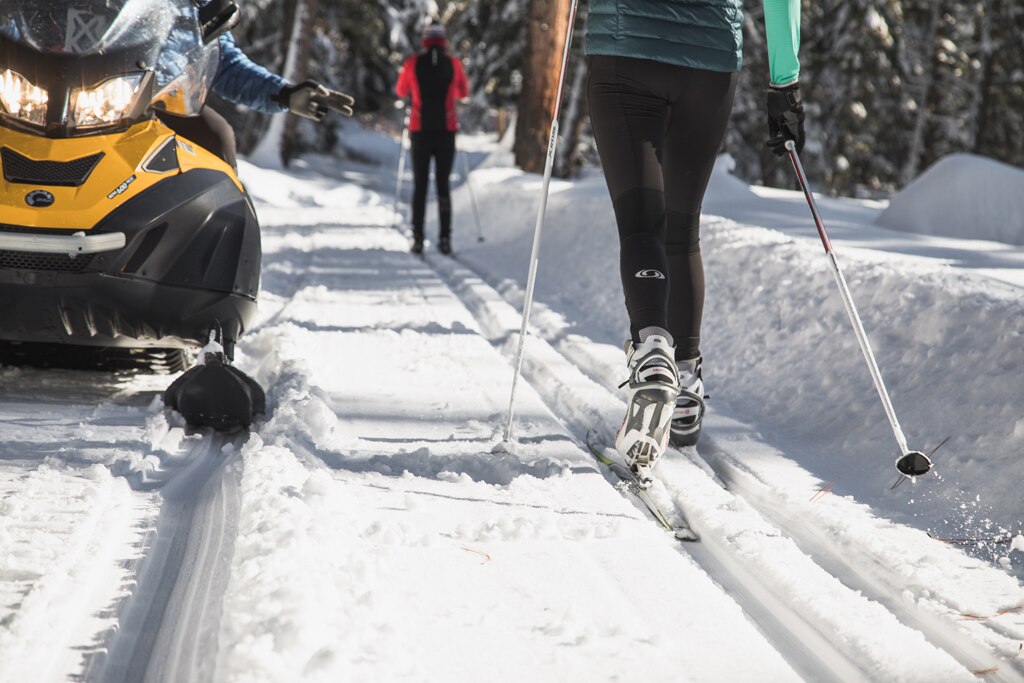 A close-up shot of cross-country skiers passing a snowmobile