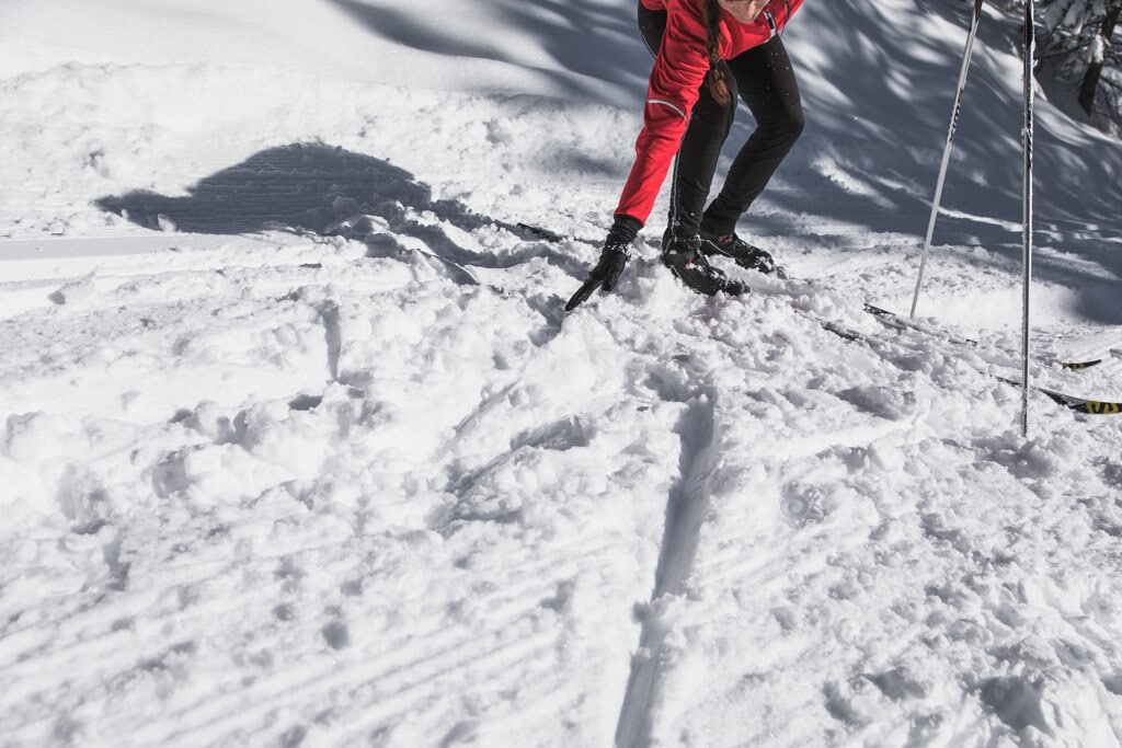 A cross-country skier fixing a divot in the track