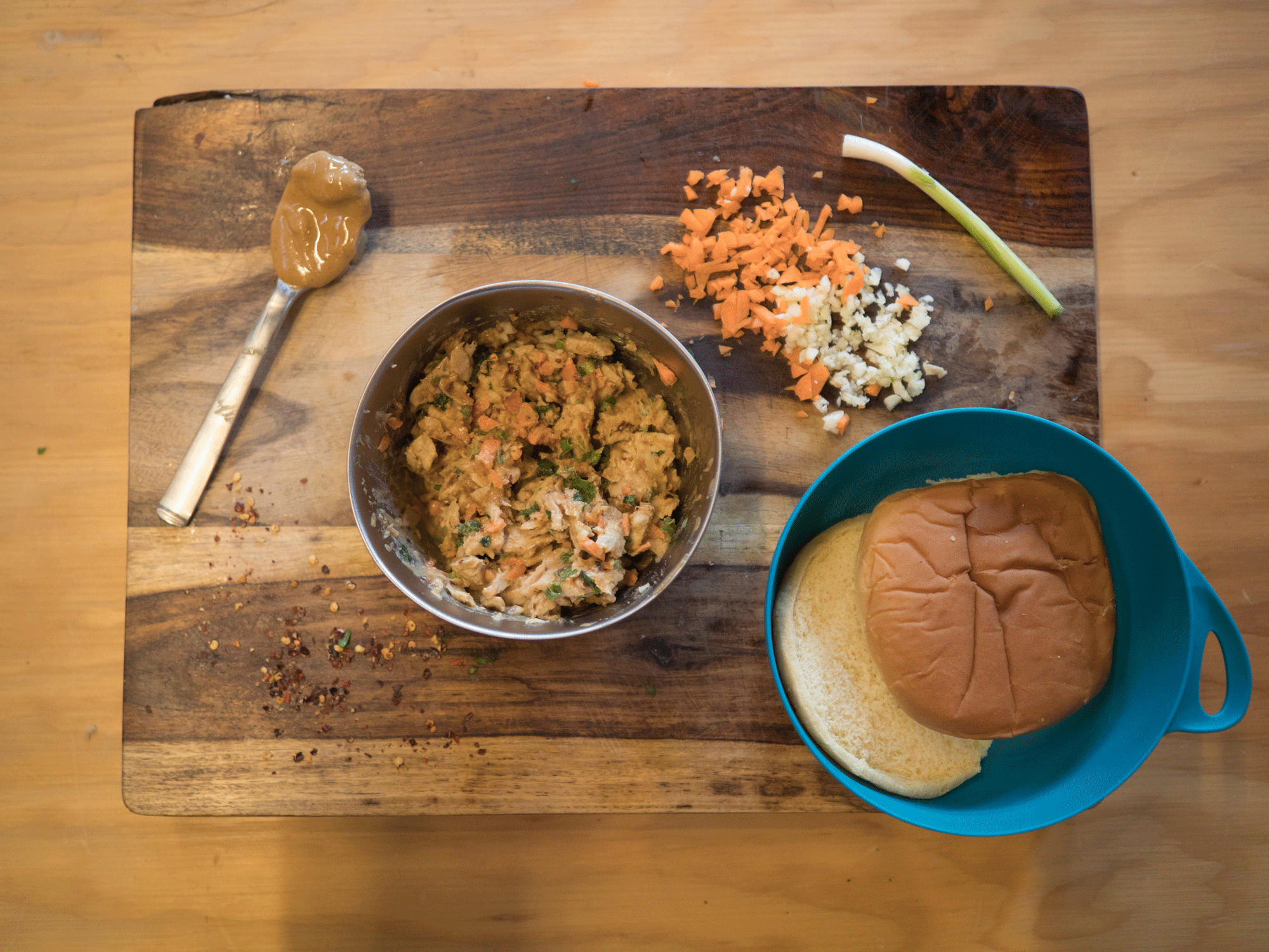 A nut butter sandwich with a bun, carrots, Thai-inspired slaw and onion all laid out