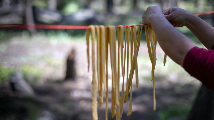 Maria Hines hangs raw pasta noodles from a rope.