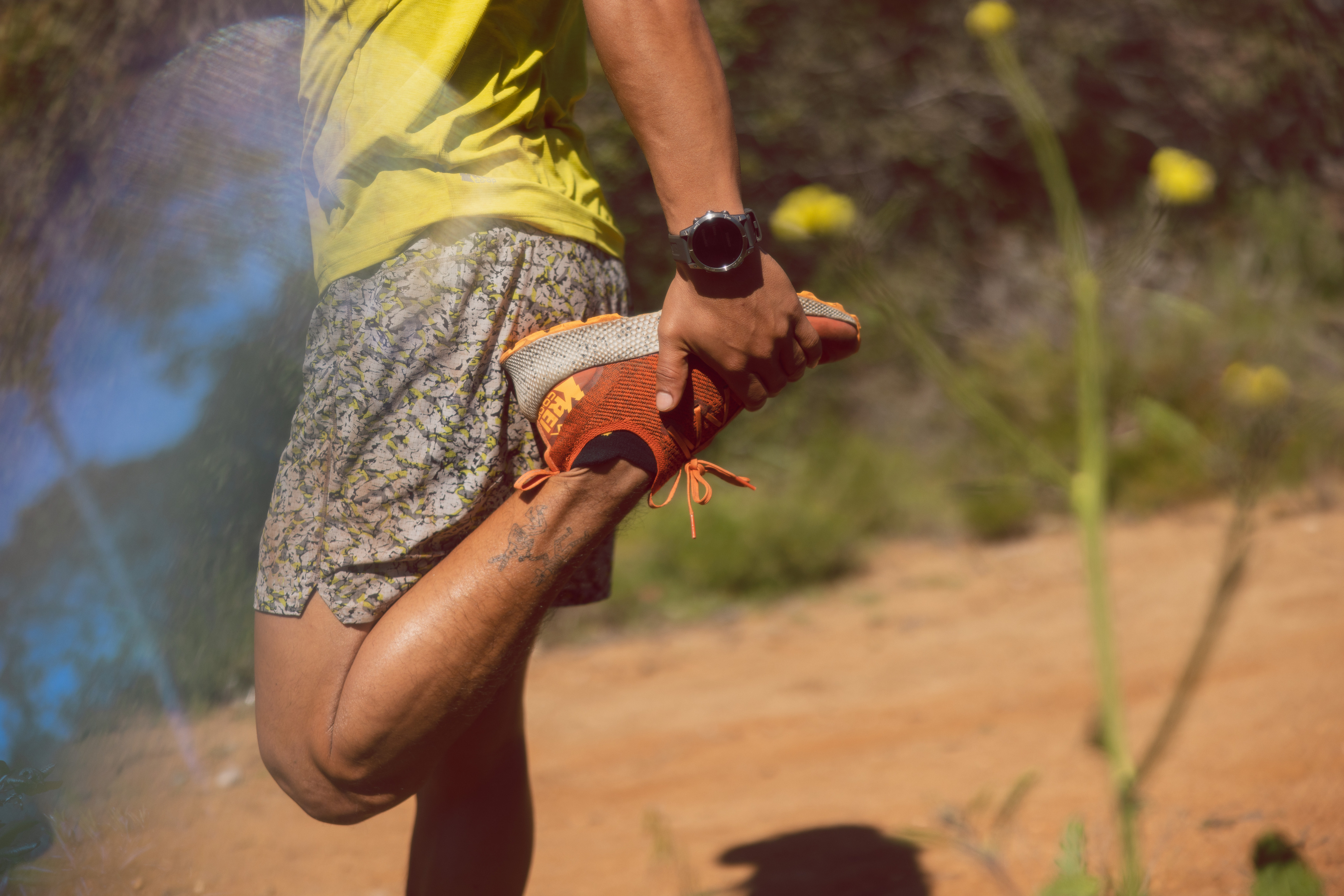 Runner stretches wearing his orange REI Swiftland trail runner shoe