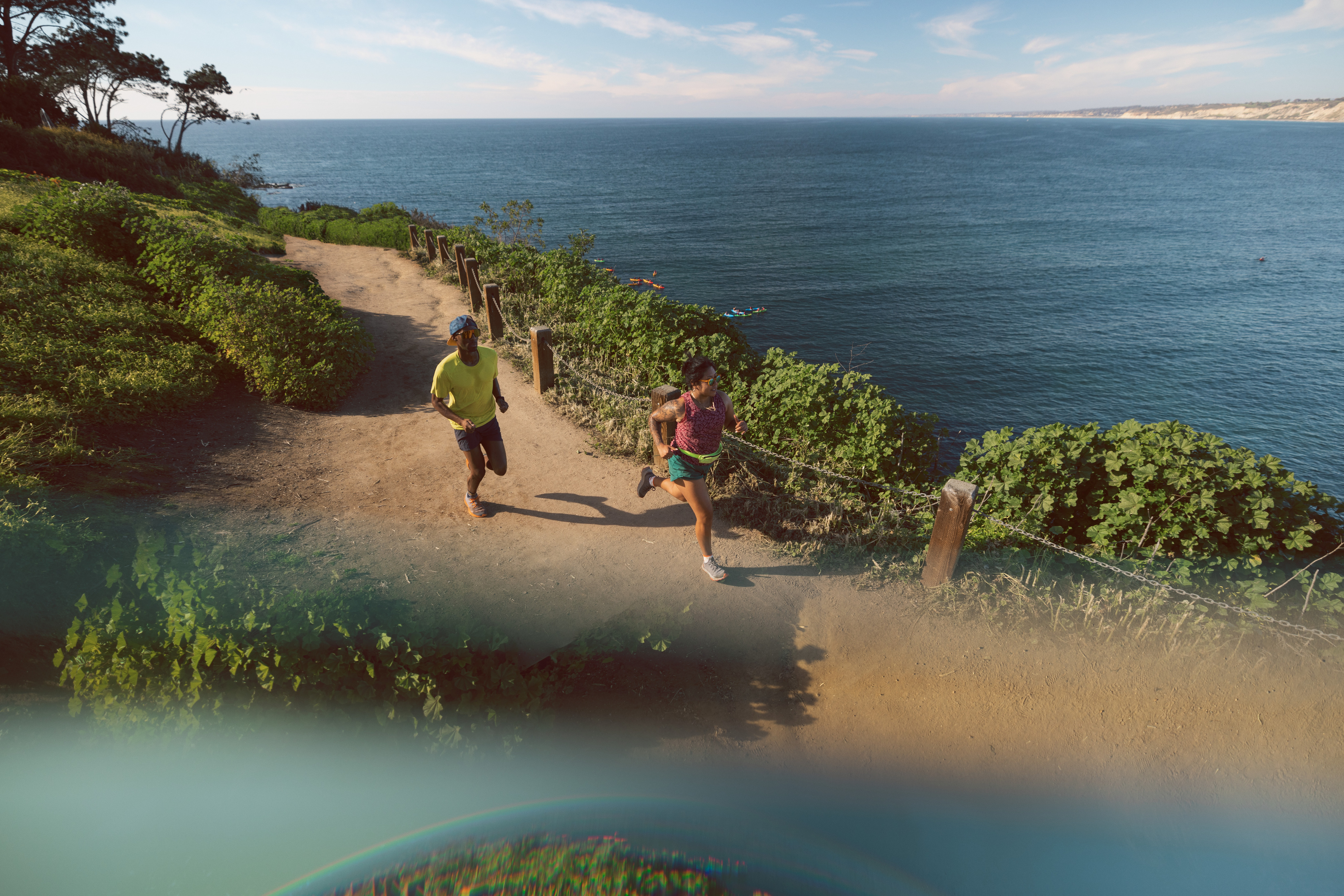 Two people run along coastline trail