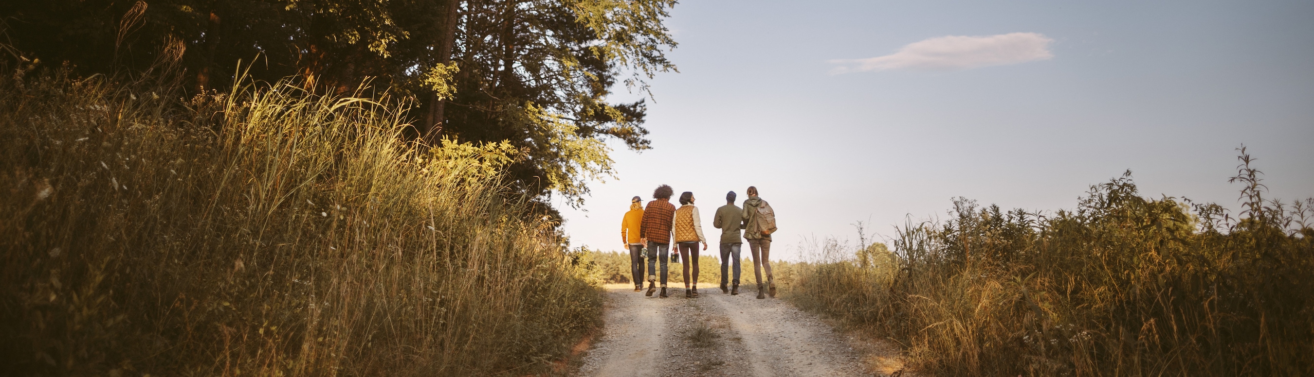 A group of friends walk down a dirt path