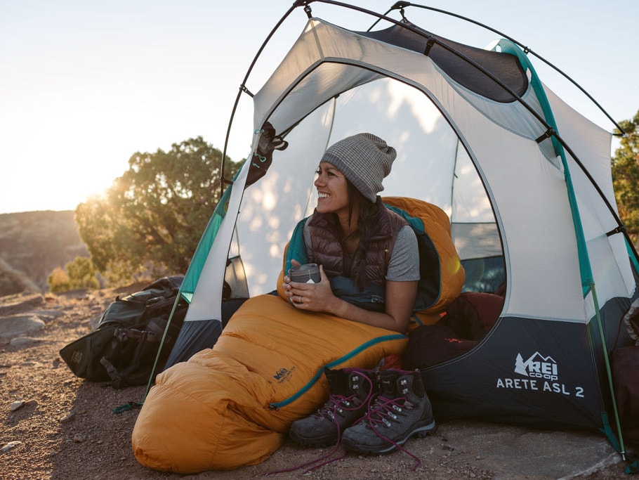 A woman sitting in a tent, looking out at the sunrise.