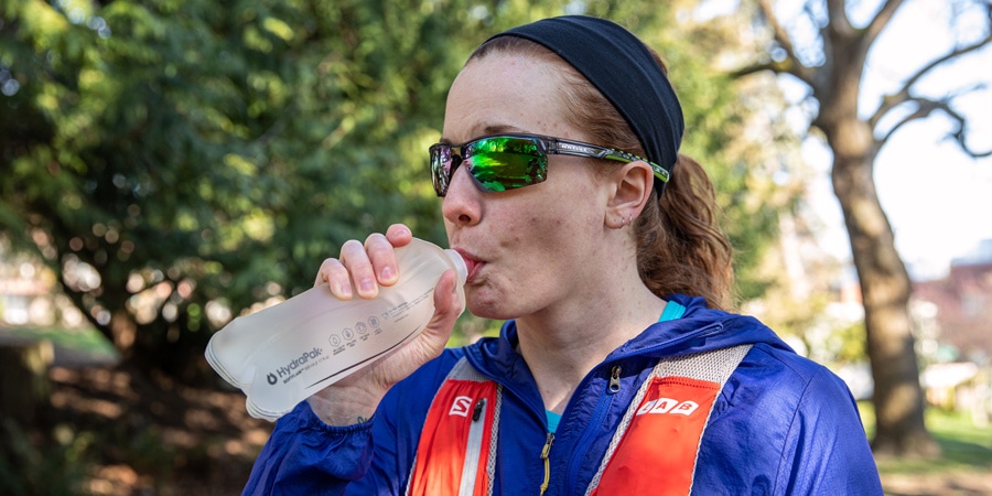 A trail runner drinking from a soft water bottle